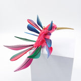 Colibrí rosa con alas de colores en madera de copal