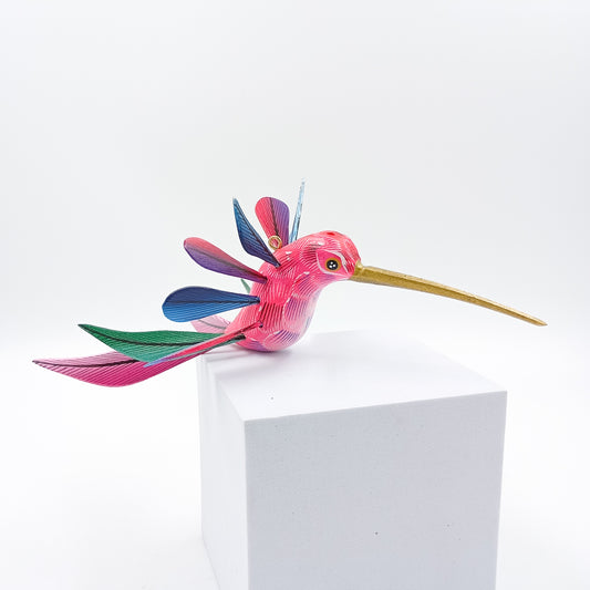 Colibrí rosa con alas de colores en madera de copal