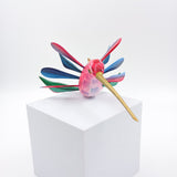 Colibrí rosa con alas de colores en madera de copal