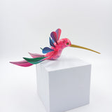 Colibrí rosa con alas de colores en madera de copal